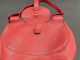 a red handbag with a leather handle and a metal clasp
