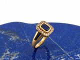 un gros plan d'une bague en or sertie d'une pierre bleue