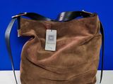 Le grand sac marron est posé sur la table, avec un mur bleu en arrière-plan.