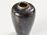 a black vase with a gold rim sitting on a white surface