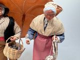two figurines of people holding baskets and an umbrella