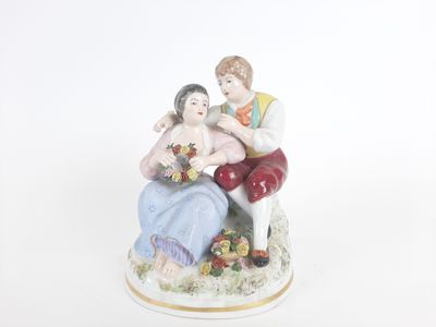 une figurine représentant un homme et une femme assis sur un banc