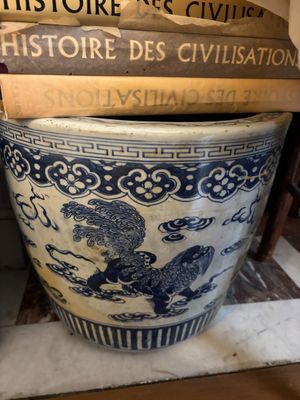 un grand vase bleu et blanc sur lequel sont empilés des livres