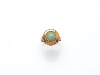 Gros plan sur une bague en or ornée d'une pierre verte
