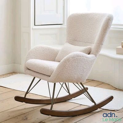 a white rocking chair in a room with a white rug