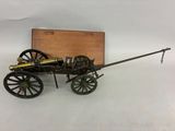 une petite maquette de canon avec une boîte en bois en arrière-plan