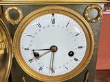 a gold and silver clock sitting on a wooden table