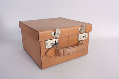 a small brown suitcase with two handles on a white surface