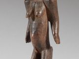 une statue en bois représentant un homme avec un sac sur le dos