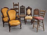 Plusieurs chaises et tabourets sont alignés sur un fond gris.