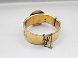 an image of a gold bracelet with a chain hanging from it