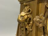 a gold clock with a lion head on it