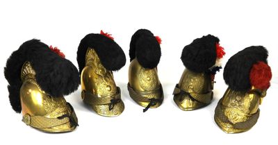 four gold shoes with black and red furs are lined up on a white surface