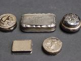 Plusieurs objets en argent sont disposés sur une table devant un fond noir