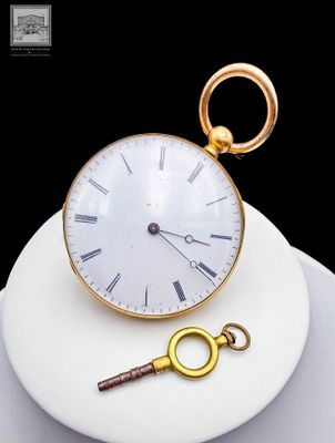 a gold clock and a key on a white plate