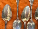 five silver spoons are lined up in a row on an orange cloth