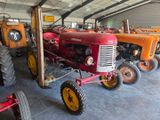 many old tractors in a large building with a number of them