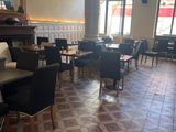 many tables and chairs in a restaurant with a fireplace in the background