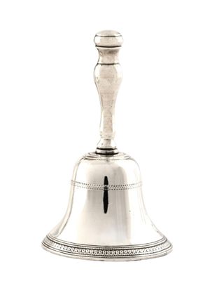 une cloche ancienne en métal argenté, posée sur un socle surmonté d'une croix