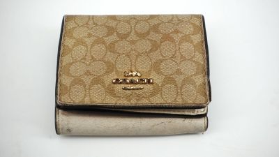 portefeuille Coach beige et noir sur fond blanc