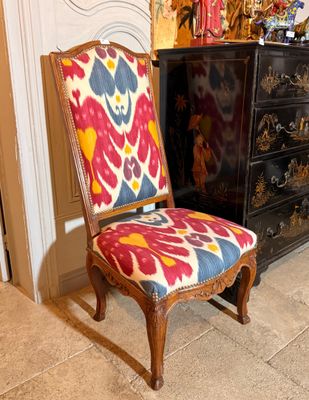 fauteuil rembourré aux couleurs vives placé devant une commode dans un salon