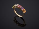 a gold ring with multi colored stones on a black surface