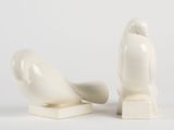 pair of white bird figurines sitting next to each other on a white surface