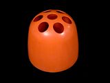 un vase orange percé de trous sur fond noir