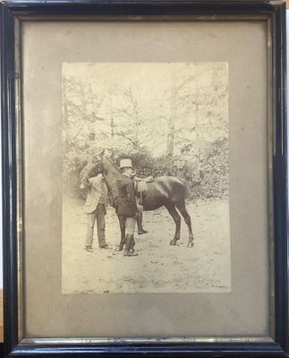 une vieille photo d'un homme debout à côté d'un cheval dans un champ