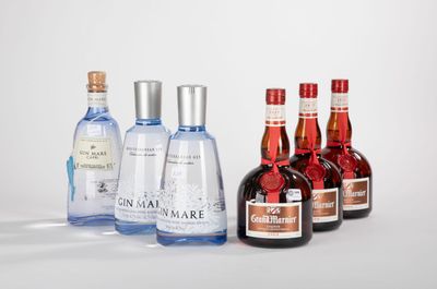 quatre bouteilles d'alcool sont alignées les unes à côté des autres sur une surface blanche