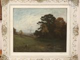 painting of a landscape in a white frame on a wooden table