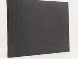 an old black book sitting on top of a white table