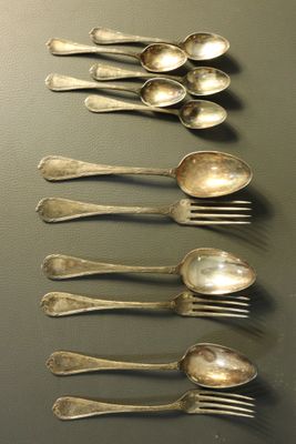 six cuillères en argent sont alignées sur une table