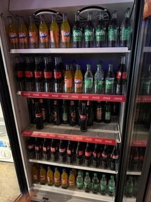Des bouteilles de soda et de boissons non alcoolisées sont exposées dans un réfrigérateur