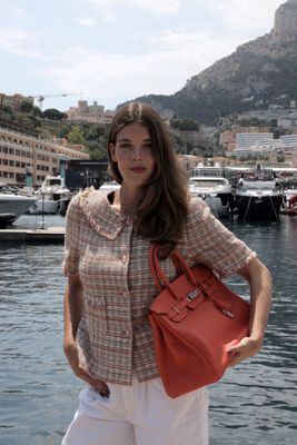 une femme qui se tient près de l'eau avec un sac