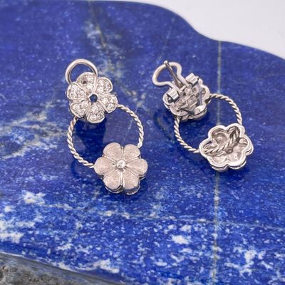 two silver flower charms on a blue stone with a white background