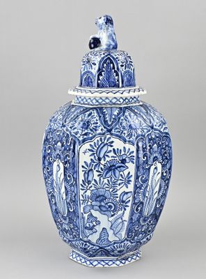 un vase bleu et blanc surmonté d'un oiseau