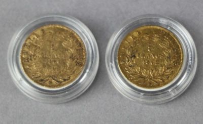 two gold coins in a clear plastic container on a gray surface