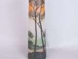 a tall vase with a painting of trees on it