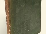 un vieux livre à la couverture verte posé sur une surface blanche