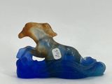 statue of a dog sitting on top of a wave in the ocean