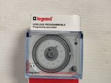 l'image d'une horloge posée sur une surface blanche, avec un socle rouge
