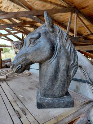 une statue représentant une tête de cheval posée sur un socle en bois