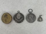 three silver and gold coins and a silver coin on a white surface
