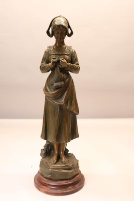 statue en bronze représentant une femme tenant un bébé dans ses bras, posée sur un socle en bois