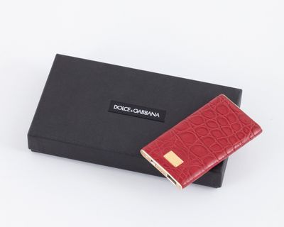 un portefeuille rouge posé à côté d'une boîte noire sur une surface blanche