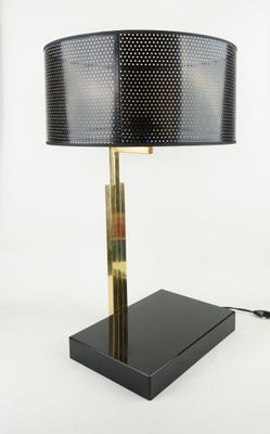 a black table lamp with a gold base and a black shade