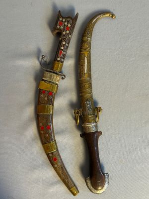une paire de couteaux anciens plaqués laiton posés sur un fond blanc