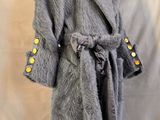 manteau de fourrure gris sur un mannequin de vitrine, orné de boutons jaunes