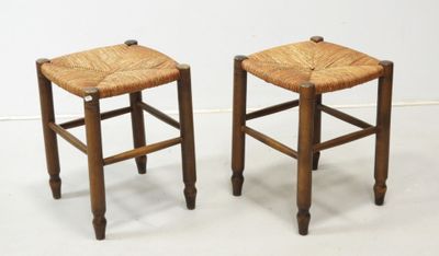 two wooden stools with wicker seats on a white surface